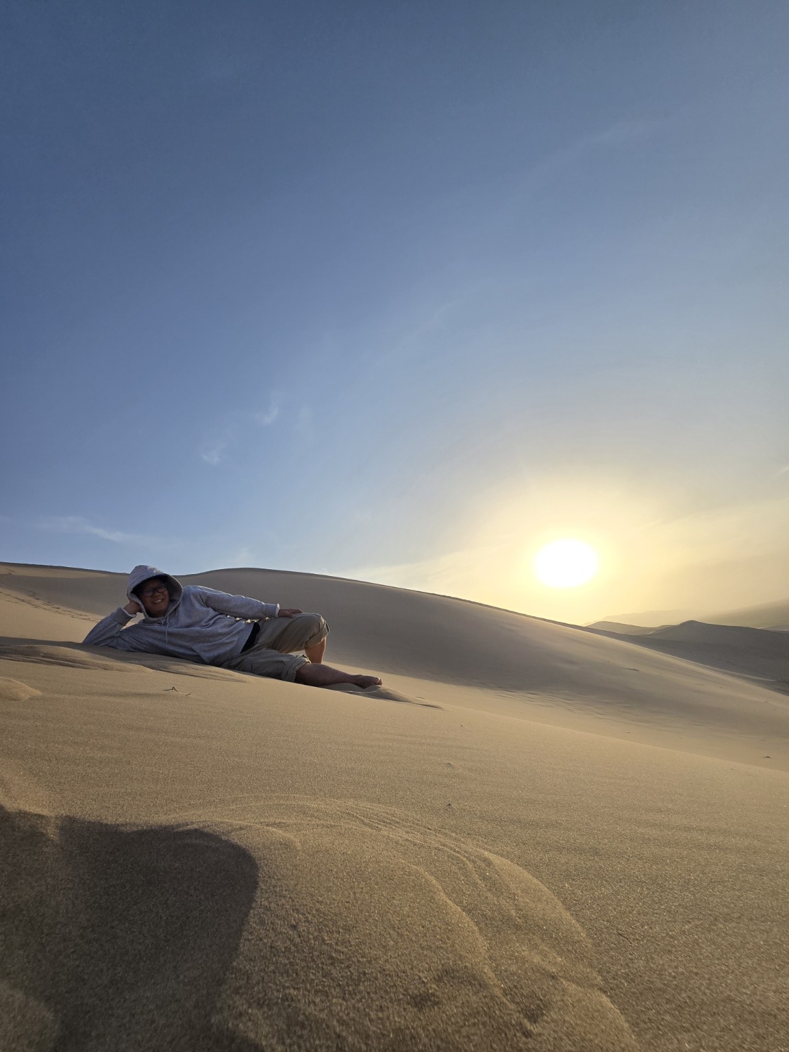 Traveler relaxing on the dunes at sunset
